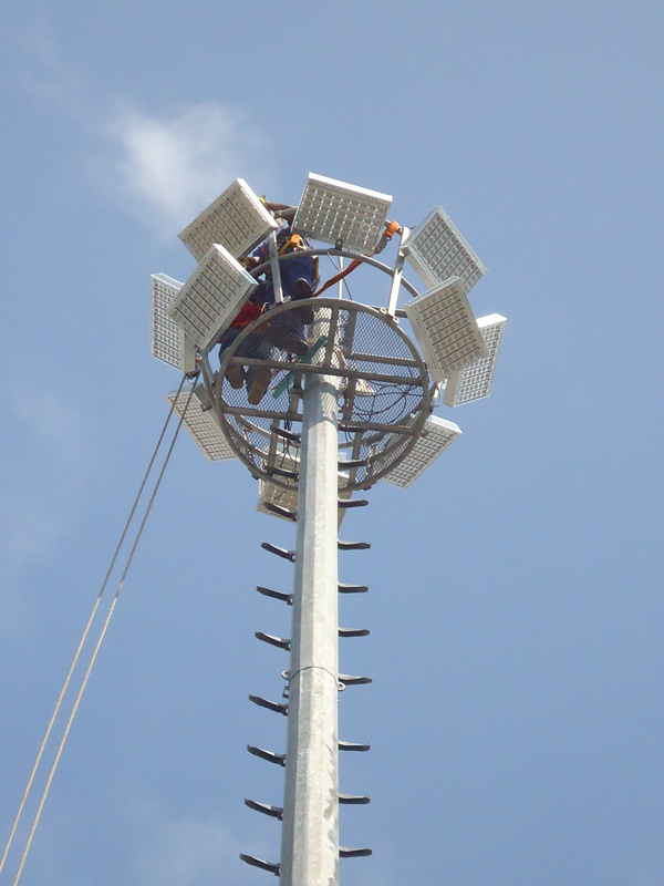 Technicians working on modular high mast LED floodlights at the top of a pole in a UK port yard