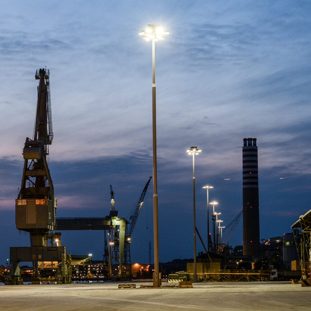 High mast LED flood lights illuminating a container yard and truck lanes at night to improve safety and visibility